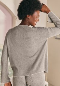 Maglione grigio a coste con vestibilità morbida, maniche ampie e dettagli a orlo grezzo. Texture soffice, ideale per un abbigliamento casual.