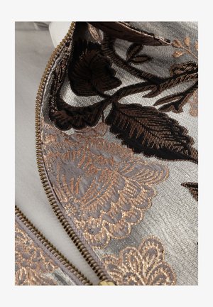 Geborduurd fabric met zilveren, zwarte en koperen bloemmotieven. Inclusief een gouden rits langs de rand, met een soepele textuur.