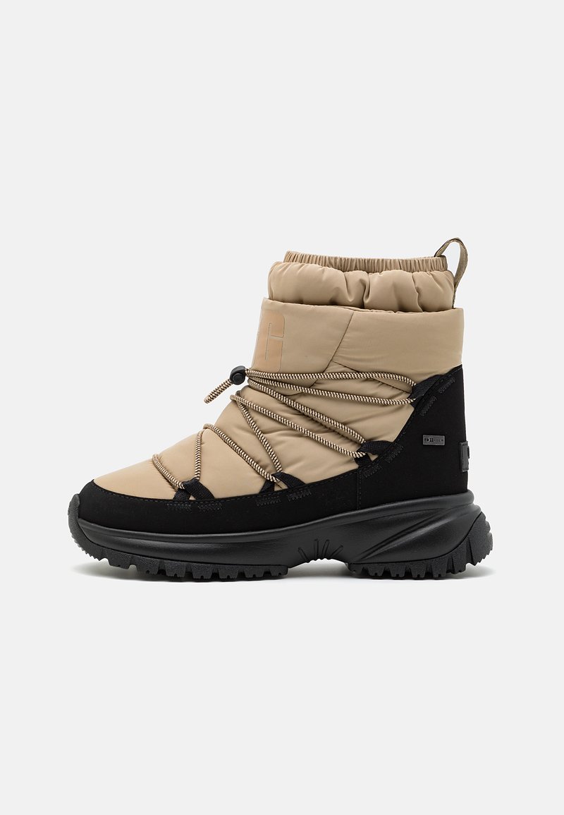 Beige wasserdichte Winterstiefel mit gerafftem Kragen, schwarzen Akzenten, elastischen Schnürsenkeln und einer strukturierten Gummisohle für guten Halt.