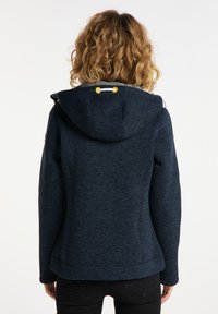Mörkblå hoodie med en texturerad mönster, som har en huva med snörning i gult och en skräddarsydd midja för en figurnära silhuett.