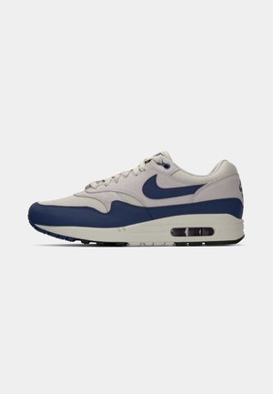Men’s sports shoe with light grey mesh and suede upper, navy blue leather overlays, navy Nike swoosh, and visible air cushion sole.