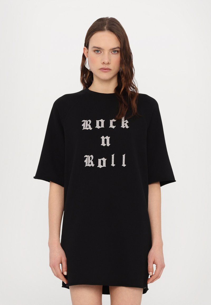 Vestido sudadera negro de gran tamaño hecho de tela suave, con "Rock n Roll" impreso en fuente gótica gris en la parte delantera. Mangas cortas.
