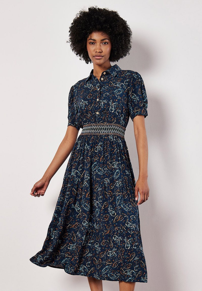 Robe bleu marine avec de courtes manches bouffantes, devant boutonné, taille smockée et motif cachemire en teal et orange, atteignant la longueur midi.