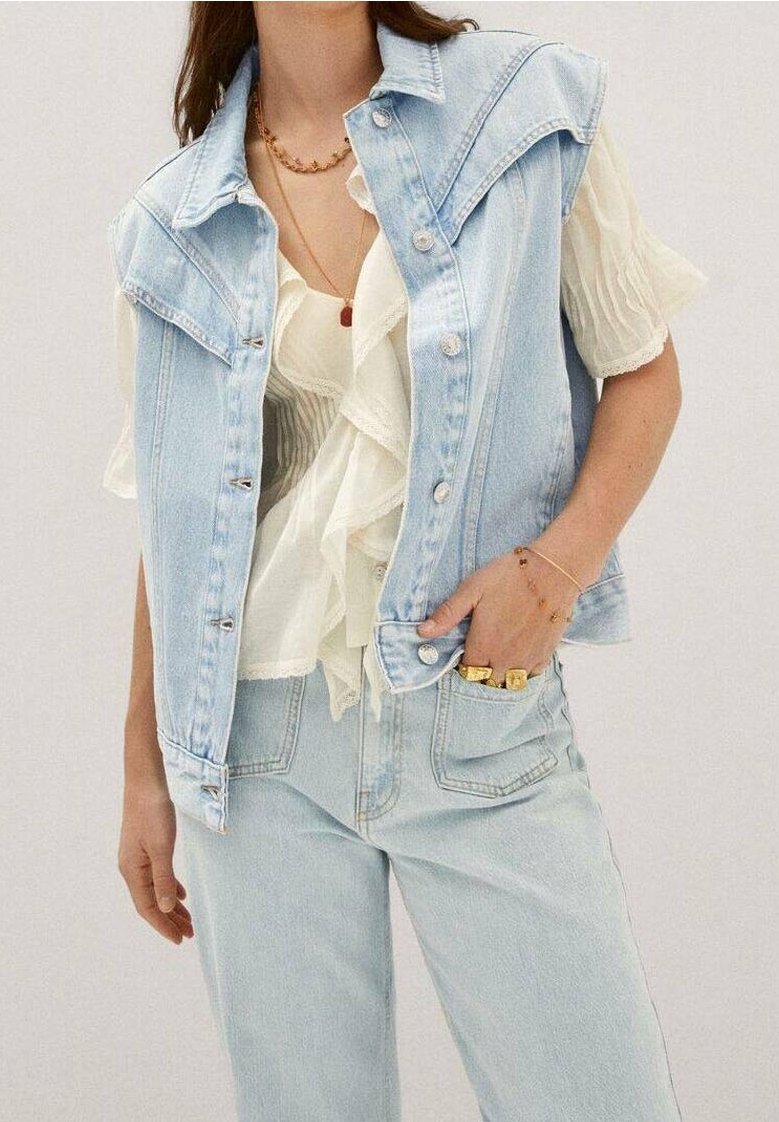 Helles blaues Denim-Westen mit strukturiertem Kragen, Edelstahlknöpfen, darunter eine mehrlagige weiße Rüschbluse und passende helle Jeans.