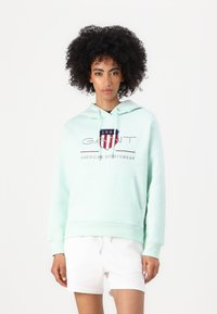 Muntgroene hoodie met een voorzak, een trekkoord capuchon en een bedrukte logo met rode, witte en blauwe accenten. Zachte stof.