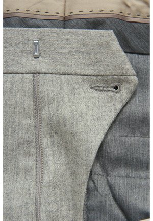 Graues Wollmischgewebe mit glatter Textur. Verfügt über einen Reißverschluss, Stichakzente und ein Taschenloch am Bund für Haltbarkeit.