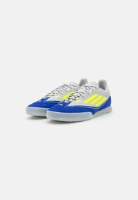 Scarpe da ginnastica blu e grigie con accenti gialli, dotate di una superficie texturizzata, chiusura con lacci e suola piatta in gomma.