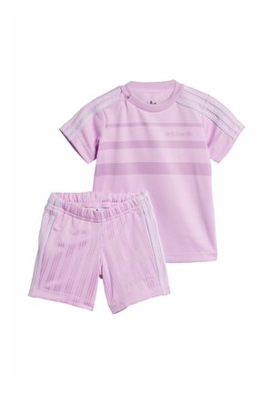 Rosa adidas Sportanzug bestehend aus einem kurzärmeligen Oberteil und passenden Shorts. Das Oberteil hat horizontale Streifen und Akzente mit drei Streifen.