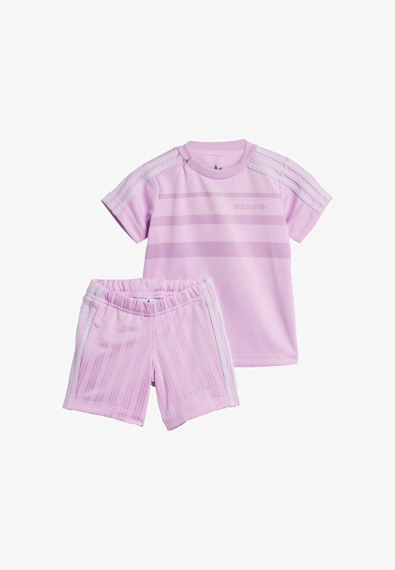 Ensemble de sport adidas rose comprenant un haut à manches courtes et un short assorti. Le haut présente des rayures horizontales et des accents à trois bandes.
