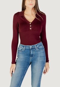 Top a maniche lunghe bordeaux a coste con colletto e tre bottoni argentati, abbinato a jeans a vita alta azzurri.