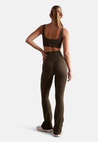 Soutien-gorge de sport côtelé vert olive et pantalon ajusté, au design sans coutures, avec taille haute et jambes évasées, le tout avec une finition texturée.