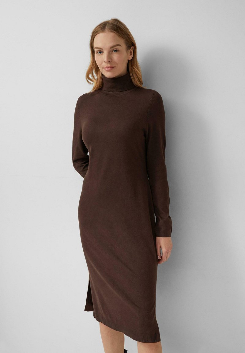 Braun gestricktes Kleid mit hohem Ausschnitt, langen Ärmeln und seitlichem Schlitz, das eine figurbetonte Silhouette und eine weiche Textur bietet.