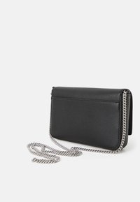 Borsa a tracolla in pelle nera con finitura testurizzata, forma rettangolare e tracolla in catena argento. Presenta una chiusura a patta e un design minimalista.