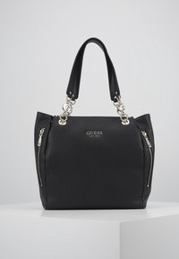 Zwarte neplederen tote bag met dubbele handvatten aan de bovenkant, accenten van zilverkleurig beslag en twee met ritssluitingen afgewerkte zijvakjes. Heeft een reliëflogo van het merk.