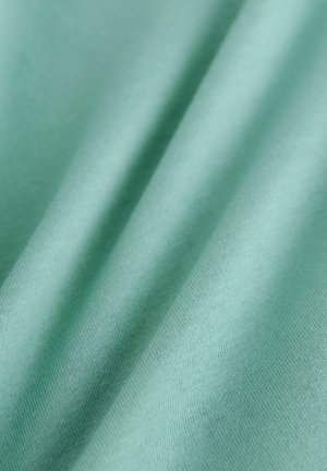 Katoenstof in een zachte mintgroene kleur met een gladde textuur, voorzien van zachte plooien die een subtiel golf effect creëren.