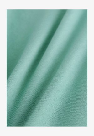 Tissu en coton d'un doux vert menthe, avec une texture lisse, présentant de douces plis qui créent un subtil effet de vague.