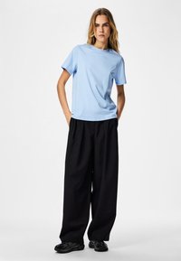 Light blue short-sleeve t-shirt made of cotton, paired with black wide-leg trousers, showcasing a relaxed fit and casual style.