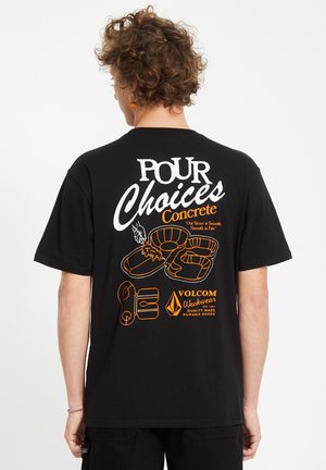 Maglietta nera con stampa grafica bianca e arancione sul retro, che mostra testo e illustrazioni di elementi legati al pattinaggio.