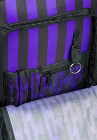 Lo zaino a strisce nero e viola presenta un interno con scomparti con zip, un portachiavi e un tessuto testurizzato con un motivo sottile.