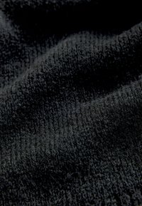 Svart textil med en mjuk, lätt ribbad yta. Materialet har en plyschkänsla och subtila variationer i skuggor.