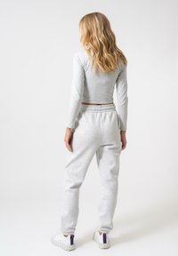 Grå langermet crop-toppar kombinert med grå joggebukser. Outfiten har elastisk midjebånd og tapered benmanchetter, supplert med hvite sneakers.