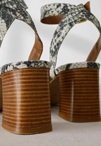 Sandali con tacco alto con tomaia a motivo di pelle di serpente in bianco e nero, tacco in legno rigato marrone e dettagli in pelle color nocciola.