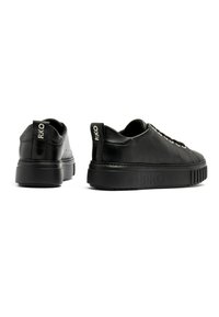 Sneakers in pelle nera con una suola spessa e texturizzata, dotati di un design con lacci e marchio RKO sul tallone e sul lato.