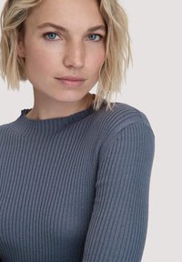 Grauer gerippter Pullover mit rundem Ausschnitt und langen Ärmeln, der aus strukturiertem Stoff gefertigt ist und einen dezenten Rüschensaum am Kragen hat.