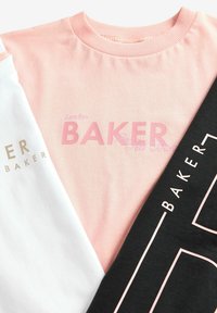 Tre t-shirts arrangeret: lyserød med "BAKER" i lys lyserød, hvid med guld logo og sort med hvid konturtekst. Stof i bomuld, afslappet design.