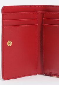 Interior de cartera de cuero rojo con múltiples ranuras para tarjetas, cierre de botón a presión y un acabado texturizado. Incluye un detalle de hardware dorado.