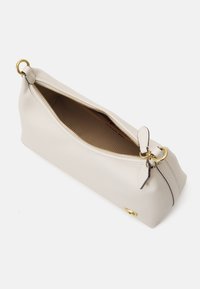 Beige leather handbag with a gold zipper, single handle, and a rounded design. Interior is lined in a contrasting brown color.