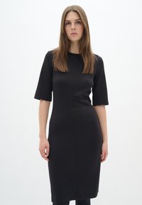 Černé šaty z pružného materiálu, s krátkými rukávy, přiléhavým střihem a délkou po kolena, s minimalistickým designem a bez vzorů.