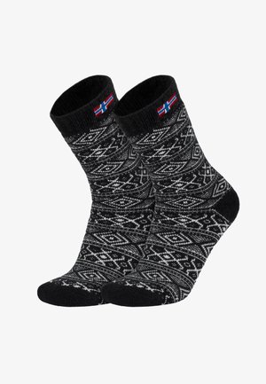 Schwarz-weiß gemusterte Socken mit geometrischem Design, weicher Textur und einem Akzent einer nordischen Flagge am Bündchen.