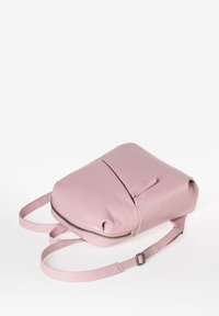 Zaino in pelle rosa con texture liscia, forma rotonda, spallacci regolabili e una tasca con zip frontale.