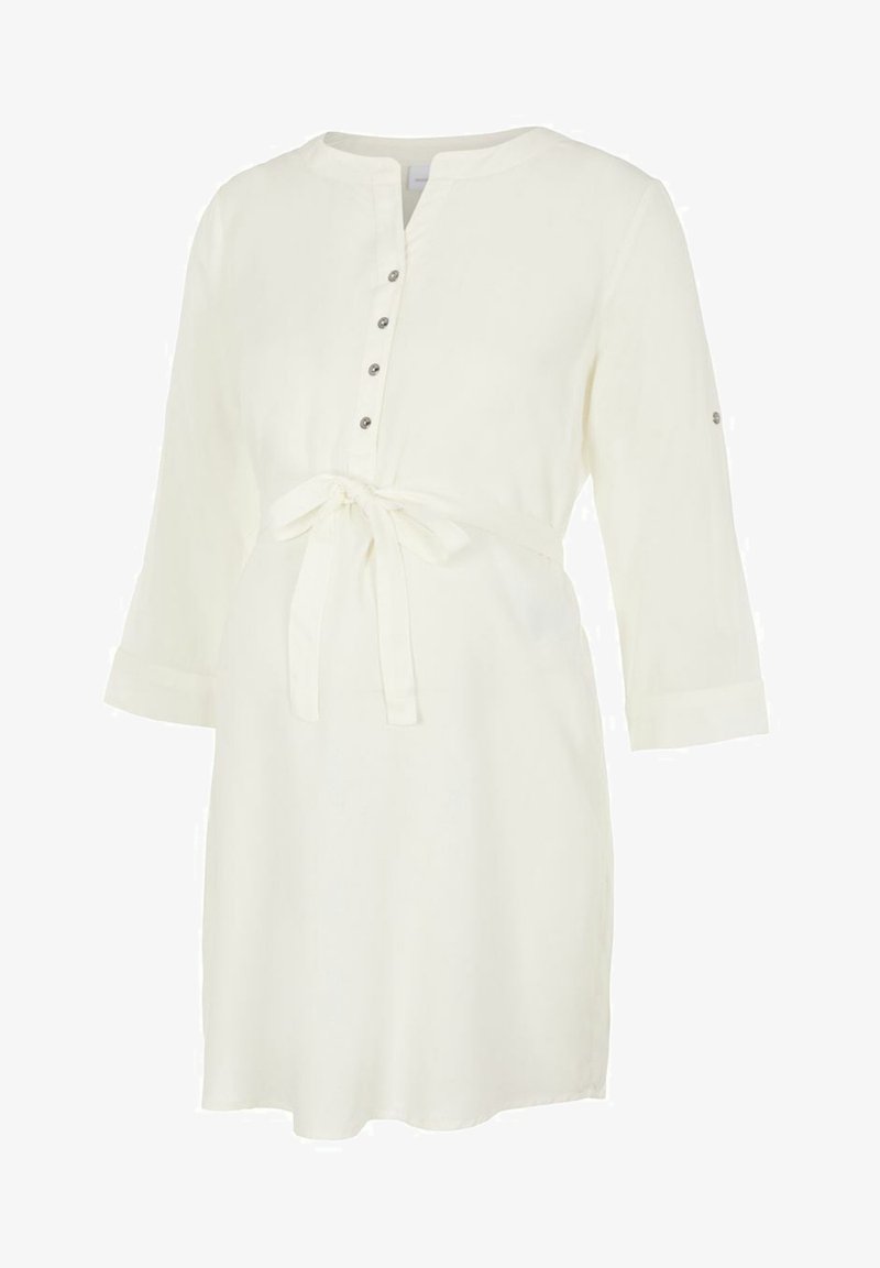 Balta, iki kelių ilgio marškininė su apvalia iškirpte, mygtukų užsegimu, ilgomis rankovėmis ir surišamu liemeniu. Lygus audinys be matomų raštų.