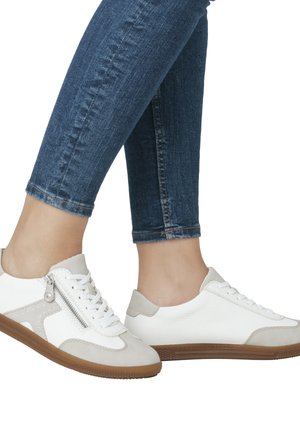 White and light grey sneakers with a textured upper, lace-up front, side zipper, and gum rubber sole. Worn with blue skinny jeans.