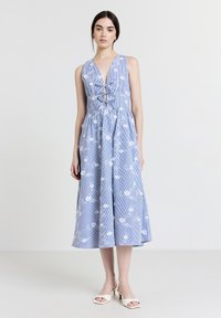 Blau-weißer gestreifter Midikleid mit Blumenmuster, V-Ausschnitt, Taillenausschnitten und ausgestellt Rock. Getragen mit weißen Absatzsandalen.