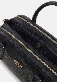 Borsa Guess in pelle nera lavorata con cerniere dorate, manico superiore e chiusura a scatto magnetica, mostrata parzialmente aperta.