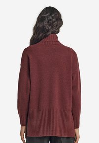 Sweter dzianinowy w głębokim burgundzie z wysokim kołnierzem, ściągaczem u dołu i na mankietach oraz luźnym krojem z opadającymi ramionami.