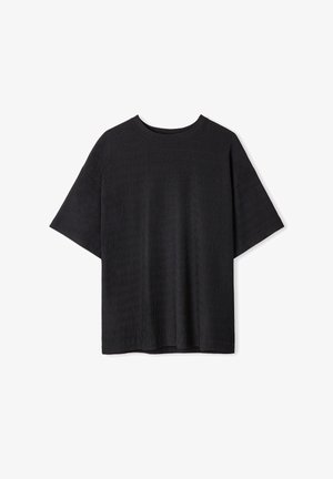 Camiseta negra de manga corta con cuello redondo, que presenta un diseño ribeteado texturizado y un corte relajado. Sin marcas ni acentos visibles.