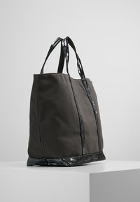 Canvas draagtas in donkergrijs met glanzende zwarte paillettenaccenten. Beschikt over stevige handvatten en een ruime, ongestructureerde ontwerp.