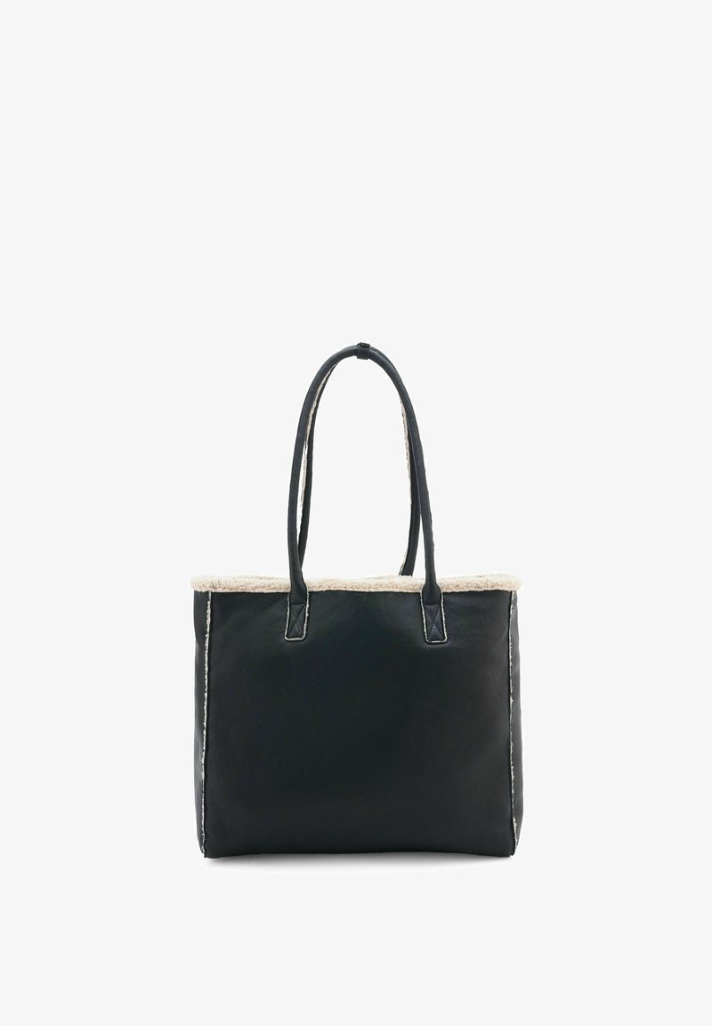 Sac fourre-tout en cuir noir avec doublure en fausse fourrure en haut, deux poignées robustes, forme rectangulaire et couture blanche le long des bords.