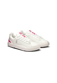 Hvide atletiske sko med pink accenter, der har en glat læderoverdel, rund tå, perforeret detaljer og en flad gummisål.