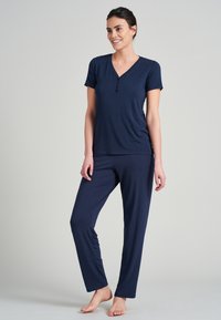 Mörkblå pyjamasset bestående av en topp med kort ärm, V-ringning och tre-knapplås, parat med raka byxor i mjukt tyg.