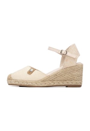 Cuña espadrille de lona beige con suela de yute trenzado, correa ajustable en el tobillo y un adorno decorativo de cuero en la parte delantera.