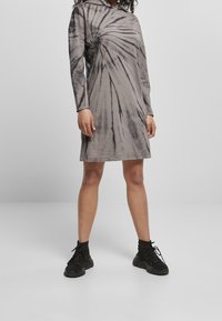 Szara sukienka tie-dye z kapturem, z długimi rękawami, w spiralny wzór i luźnym kroju, wykonana z miękkiego bawełnianego materiału.