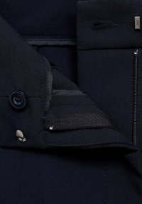 Čierna tkanina s hladkou textúrou; obsahuje gombík, zips a elastický pás; zahŕňa presné šitie a elegantný dizajn.