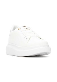 Zapatilla blanca con suela plana y elevada. Fabricada en material suave, con diseño de cordones, ojales de metal y un logotipo mínimo en el lateral.