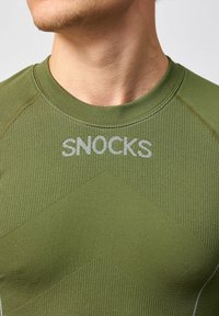 Groen sportshirt met een gestructureerd ontwerp, ronde halslijn en het "SNOCKS" logo in lichtgrijs op de borst. Glad stofafwerking.