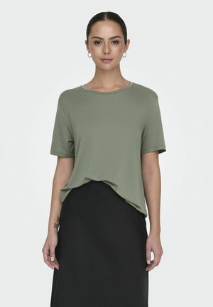 T-shirt vert olive à manches courtes avec un col rond, légèrement ample, associé à une jupe noire. Texture de tissu lisse et doux.